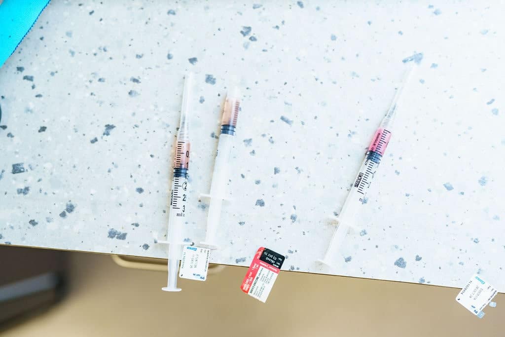 Three dog vaccines full of medicine laying on countertop